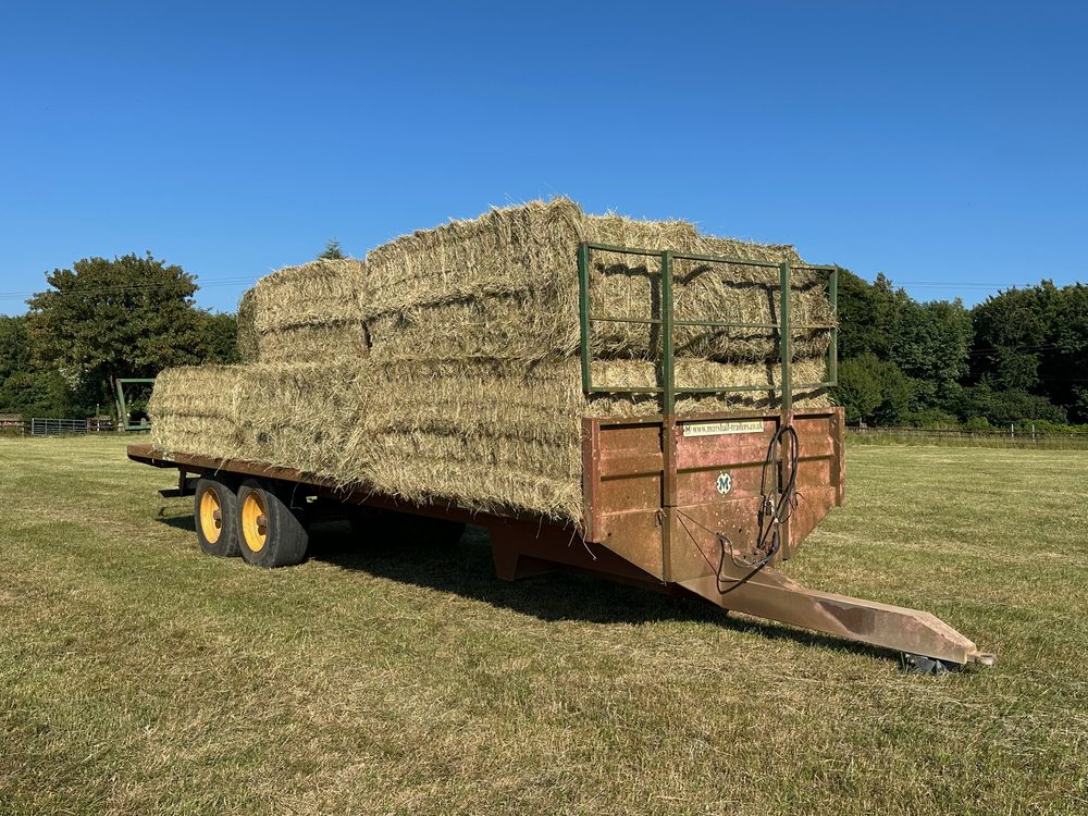 A trailer loaded with hay bales on the cut field